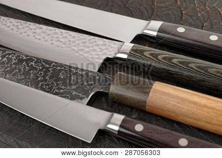 Knife handles and blades close-up on black wooden cutting board