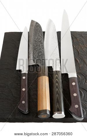 Four different knives on black wooden cutting board