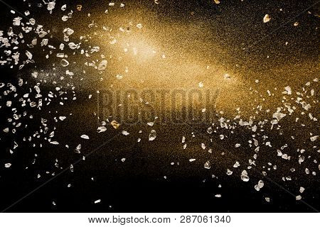 Split Debris Of Stone Exploding With Golden Dry River Sand Against Black Background.