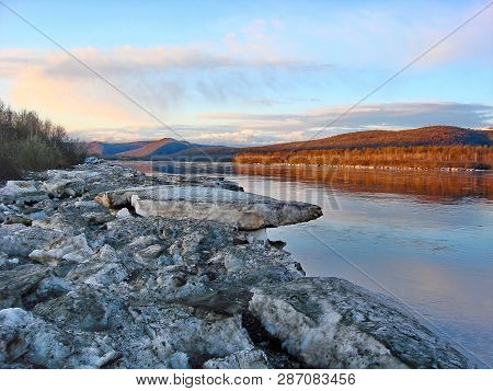 On The Shore Of A Pile Of Old Snow And Ice After The Ice Drift. Spring. The River Is Free Of Ice.