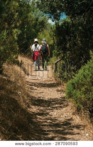 Monfrague Park, Spain - July 04, 2018. People Walking Along Dirt Path Amid Bushes And Trees On A Sun