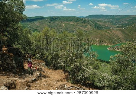 Monfrague Park, Spain - July 04, 2018. Woman Walking Through Dirt Path Amid Forest Glade On A Sunny 