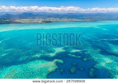 Aerial View Of Idyllic Azure Turquoise Blue Lagoon Of West Coast Barrier Reef, With Mountains Far In