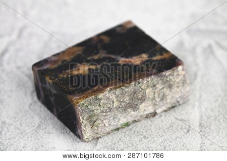 Natural Mineral Stone - Polished Charoite Gemstone On White Cement Background.
