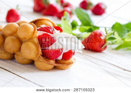 Waffles With Strawberries And Whipped Cream On The Wooden Table