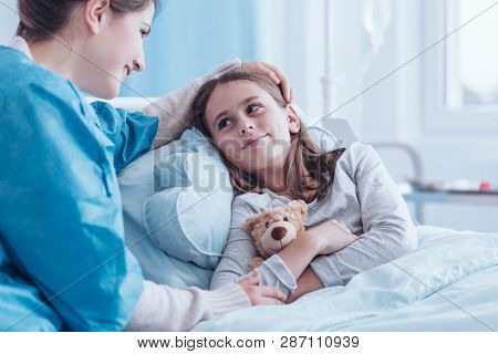 Smiling Caregiver Visiting Happy, Sick Girl In The Health Center