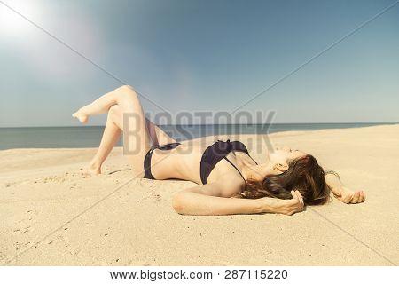 Beautiful Young Woman In Swimsuit At Sand Sea Beach Under Light Rays