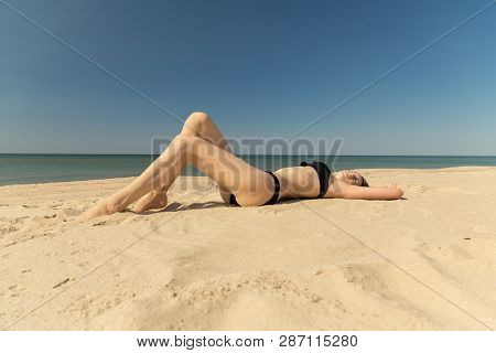 Beautiful Young Woman In Swimsuit At Sand Sea Beach Under Light Rays