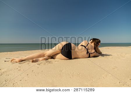Beautiful Young Woman In Swimsuit At Sand Sea Beach Under Light Rays
