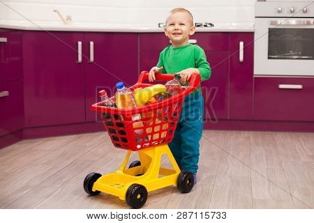 Cheerful Little Boy With Shopping Cart. Little Kid In Casual Wear Carrying Child Plastic Shopping Tr