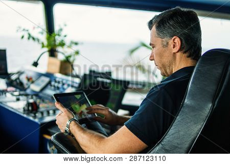 Chief Officer On Navigation Bridge Watching Digital Tablet.