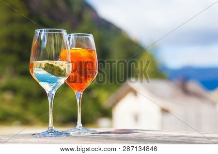 Chilled Aperol Spritz And Prosesso Glasses Over Mountains Background