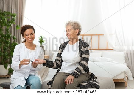 Doctor Measuring Patient's Blood Sugar Level With Digital Glucose Meter At Home. Diabetes Control