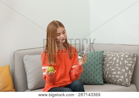 Teen Girl Holding Digital Glucometer And Apple At Home. Diabetes Diet