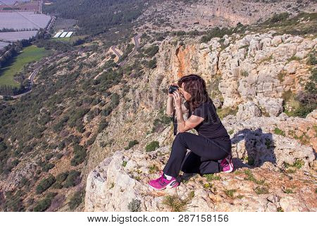 Nahariyya, Israel - Februar 19, 2016 : Woman In A Black Tracksuit Photographing Sitting On The Edge 