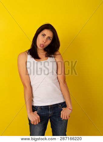 Pretty Girl With Dark Hair In Casual Clothes In Good Mood Makes A Wry Face And Makes A Face On A Bri