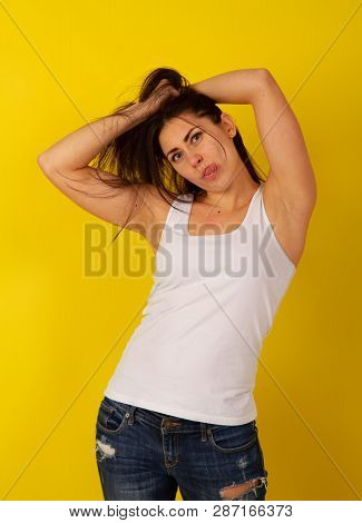 Pretty Girl With Dark Hair In Casual Clothes In Good Mood Makes A Wry Face And Makes A Face On A Bri