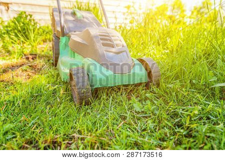 Lawn Mower Cutting Green Grass In Backyard In Sunny Day. Gardening Country Lifestyle Background. Bea