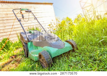 Lawn Mower Cutting Green Grass In Backyard In Sunny Day. Gardening Country Lifestyle Background. Bea