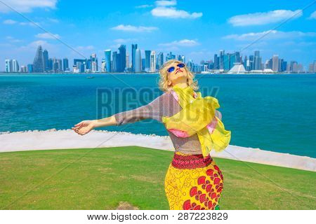 Qatar Travel Concept. Carefree Caucasian Woman Enjoyis The Views Of Doha West Bay. Blonde Tourist At