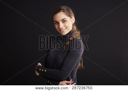 Attractive Young Woman Studio Portrait While Standing At Dark Background