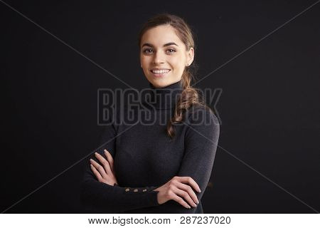Attractive Young Woman Studio Portrait While Standing At Dark Background