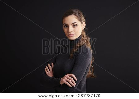 Attractive Young Woman Studio Portrait While Standing At Dark Background