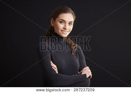 Attractive Young Woman Studio Portrait While Standing At Dark Background
