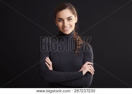 Attractive Young Woman Studio Portrait While Standing At Dark Background