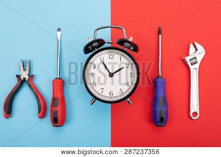 Set Of Tools With Alarm Clock Isolated On Blue-red Background