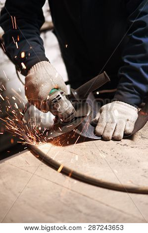 Vertical Photo Of Blacksmith Grindering A Metal Plate Holding An Angle Grinder. The Blacksmith Work 