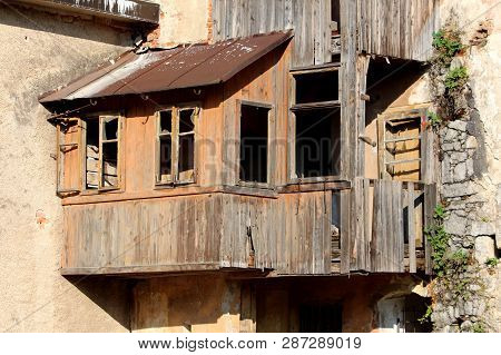 Ruins Of Wooden House Addon With Destroyed Boards And Missing Glass On Windows And With Rusted Roof 