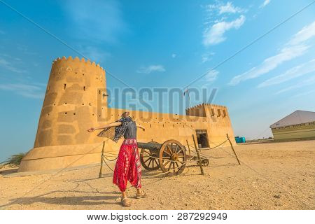 Traveler In North Of Qatar. Carefree Woman At Al Zubara Fort, A Historic Qatari Military Fortress, M