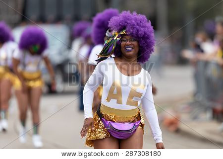 New Orleans, Louisiana, USA - February 23, 2019: Mardi Gras Parade, Alter Egos Steppers, African american dancer, smiling , wearing a purple wig, dancing during the parade