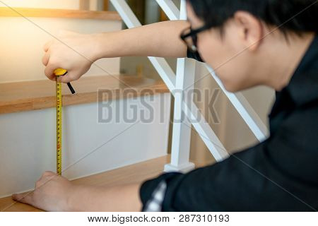 Young Asian Worker Using Tape Measure For Measuring Riser And Thread On Stair In The House. Housing 