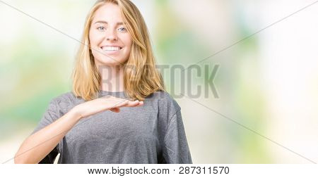 Beautiful young woman wearing oversize casual t-shirt over isolated background gesturing with hands showing big and large size sign, measure symbol. Smiling looking at the camera. Measuring concept.