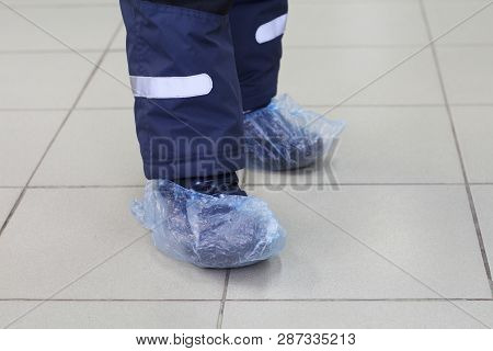 Feet In Blue Shoe Covers. In The Photo Are Two Children Feet In Shoe Covers. The Floor Is Clean. Com