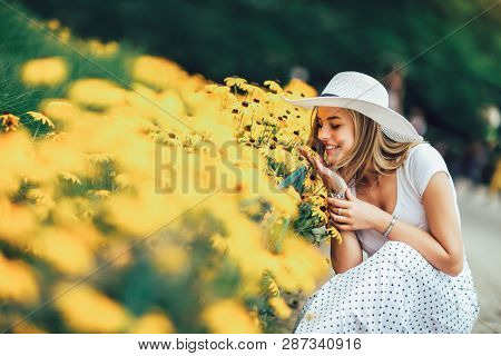 Beautiful Young Woman Smelling Yellow Flower In The Park.