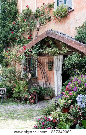 Colourful Entrance Of A Countryhouse, Decoration Of Many Flowers In Many Vases Around The Door
