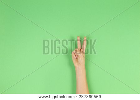 Kid Hand With Two Fingers Up On Green Background. Number Two, Peace Or Victory Symbol