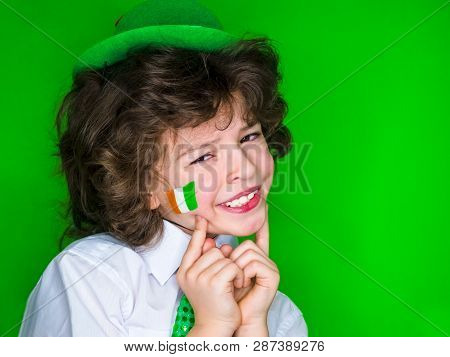 Child Celebrating St. Patricks Day Showing His Make-up. A Small, Curly Boy In Green Carnival Accesso
