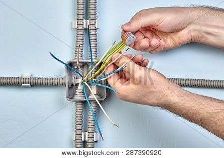 Electrician Uses Spring Terminals To Bind Wires Together Durind Mounting Electrical Junction Box.