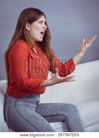 Angry, Pissed Off Young Woman. Attractive Female With Long Brown Hair Sitting On Sofa Being Mad And 