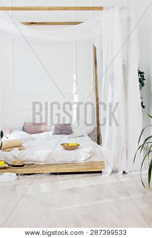 Beautiful Bright Room And A Four-poster Bed. Cozy Bedroom In Light Colors With A Wooden Floor, A Lar