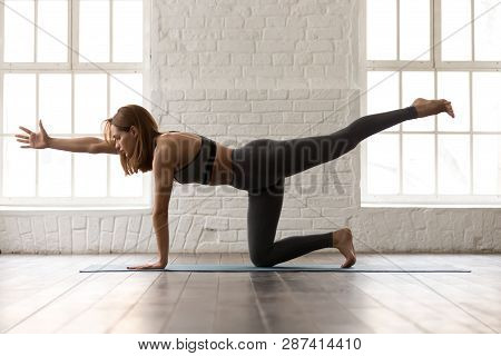 Woman Practicing Yoga, Standing In Bird Dog Pose, Donkey Kick