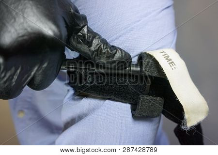 Person In Black Medical Gloves Applies The Tourniquet To His Hand To Prevent Bleeding During The Fir