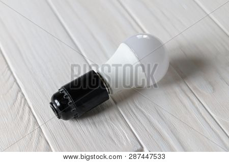 Led Light In A Dark Base. Lies On A Wooden Background. White Color