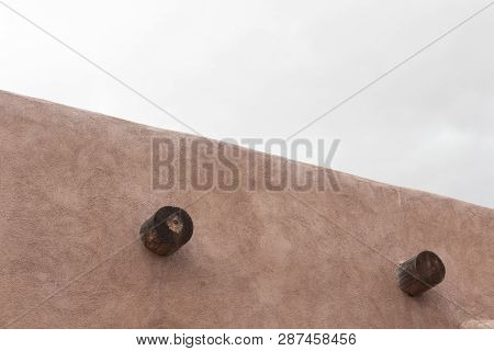Exterior Of Red Adobe Building, Two Exposed Vigas, Grey Cloudy Skies, Horizontal Aspect