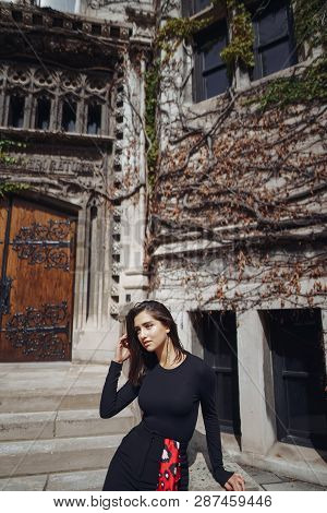 Stylish Brunette Standing Next To The Entance To A Building