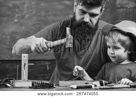 Workshop And Handyman Concept. Boy, Child Busy In Protective Helmet Learning To Hammering Hobnails W